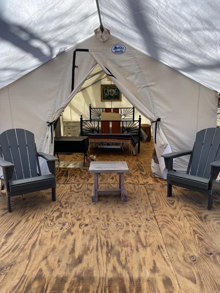 A tent with two chairs and a table in front of it.